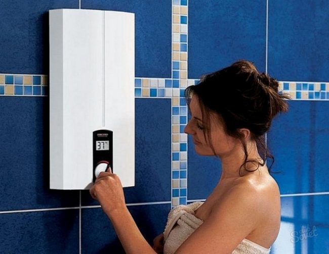 uma garota fica perto de um aquecedor elétrico de água